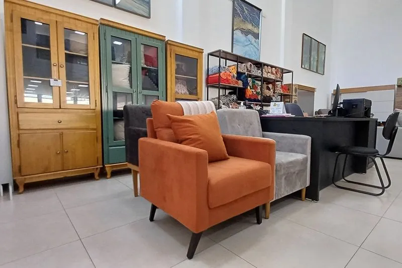 Poltrona laranja e móveis expostos no showroom da Charles Móveis